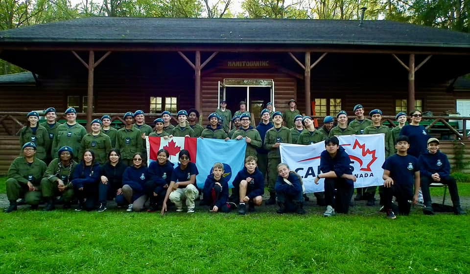23 Squadron cadets gathered together for a group photo outdoors with Canadian and Cadets Canada flags